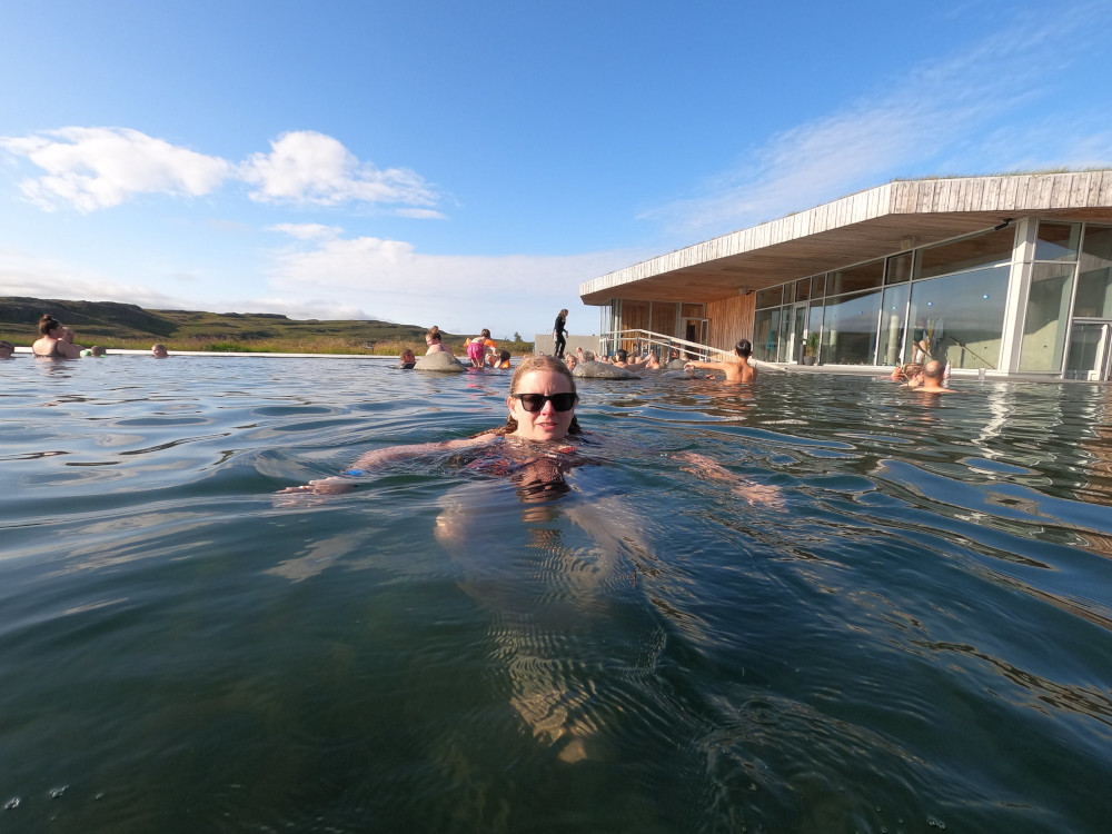 A selfie floating in the bar pool back on solid land, with the building looming over it to the right.