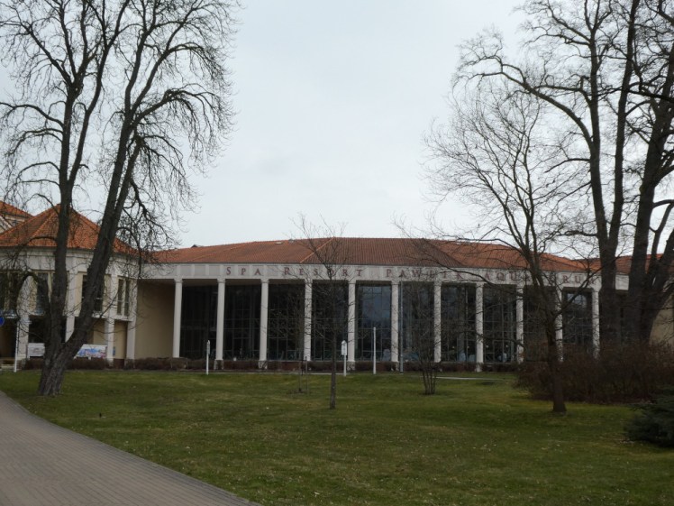 Aquaforum as seen from the spa park. It's a cream-coloured building with a red roof, slightly curved and with stone pillars holding up the roof leaving double-height glass windows between them. If you were a bit closer, you'd see the central pool area inside but I thought holding a camera up to a pool window might be considered, at best, a bit creepy.