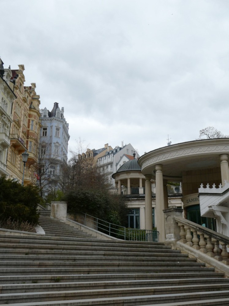 The steps up from just past the Market Colonnade, showing elaborate buildings almost looming over the steps on the left and something circular with stone pillars supporting it on the right. This is apparently the Castle Colonnade.