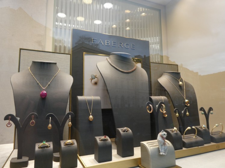 A selection of Fabergé jewellery on black stands in a shop window. For all the prestige of the brand, I'm not a fan of the dull gold finish on most of the pieces.