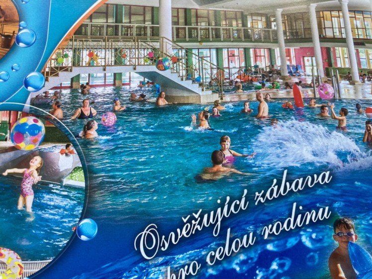 Since you can't take pictures in a public pool, a photo from the brochure showing lots of people splashing joyously around inside. There's a kind of fountain under the water to the right and a bridge overhead to the left so sunbathers and staff can shortcut across the pool.