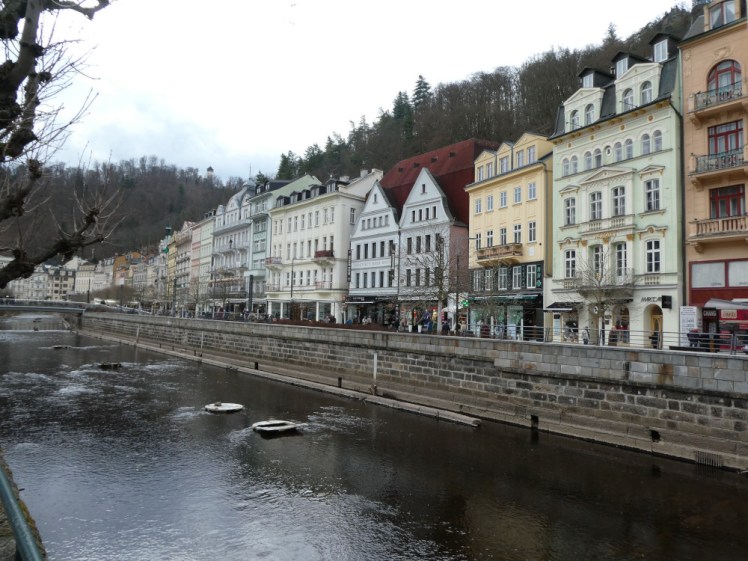 A view of Karlovy Vary. The river runs through the middle of the spa, contained by brick banks and then the buildings along the banks are colourful and vaguely Germanic.