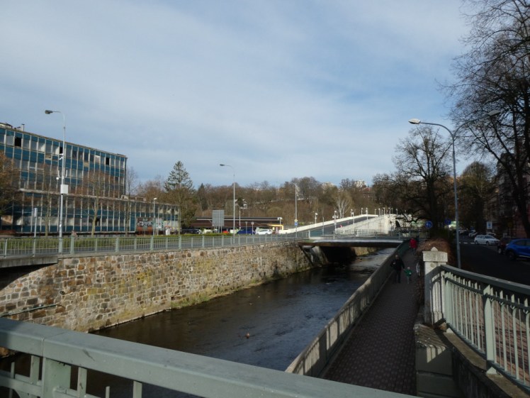The road up from Karlovy Vary to the upper station. Down here, we're alongside the river, which is contained within straight stone walls. Behind it, a road bridge rises up sharply to the ledge above the spa part of town where the station sits.