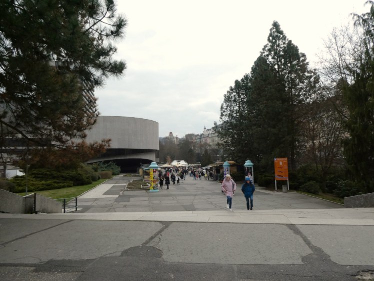 People walking up a concrete path and mingling outside stalls outside a round circular concrete thing that turned out to be the conference hall stuck on the front of the Hotel Thermal. There aren't all that many people but it's a lot compared to the last two very small, very quiet spa towns.