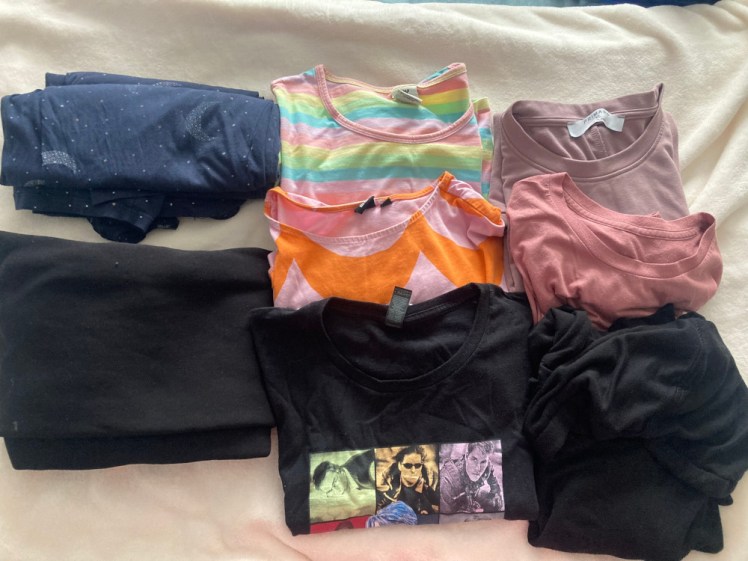 The clothes I'm packing - navy starry pyjamas, leggings, four pink/purple/patterned t-shirts, a black t-shirt and a thin black hoodie.