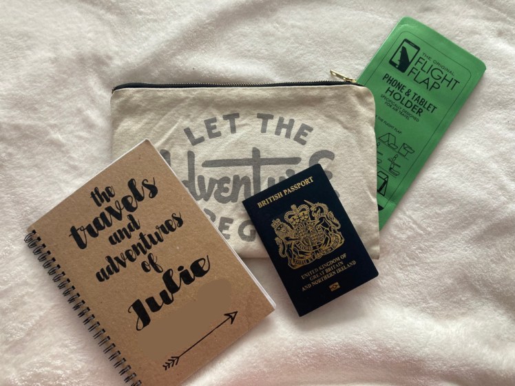 My passport pouch, a canvas pouch containing my passport, a notebook with my name on it and a piece of foam that folds into a phone stand.