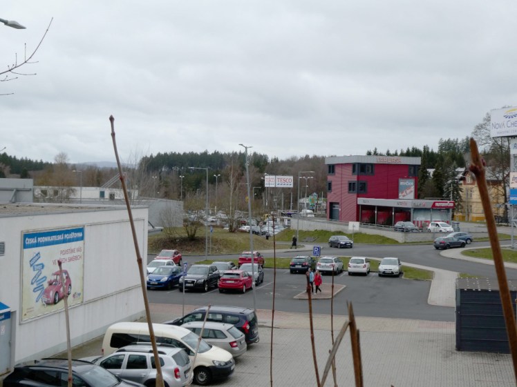 An out of town shopping centre. In the middle is a big Tesco sign, there are at least two supermarkets to the right and a smaller building housing several shops to the left.
