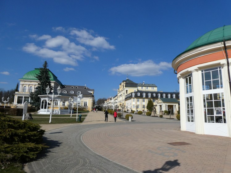 The centre of town. Yellow hotels line two sides of a largely pedestrianised street, leading down to a square with spa buildings on the right which you can't see because there's a round sort of pavilion housing a spring blocking the view of it.