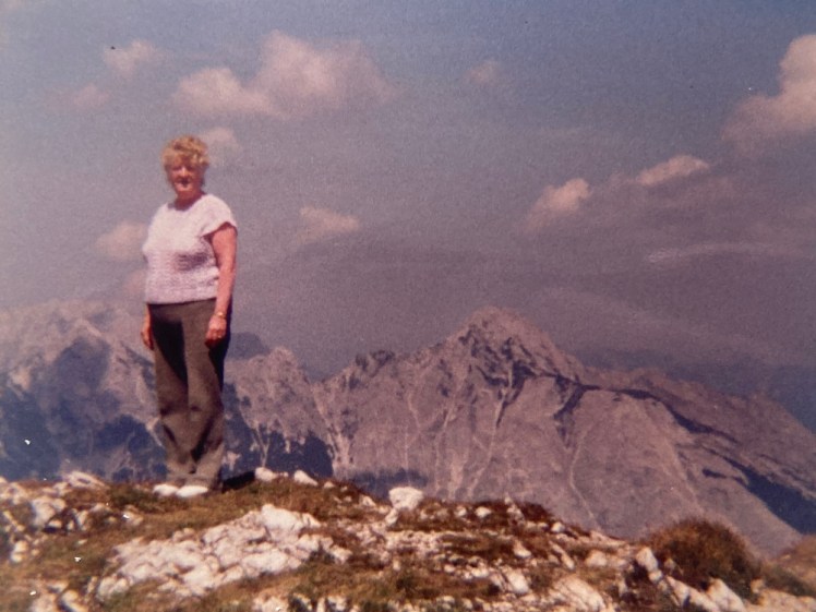 My grandmother on a mountain aged 60-ish in 1990, wearing a t-shirt and trousers that she would have called "fawn" and looking more adventurous than I ever saw her, although no doubt there's a coach just out of shot.