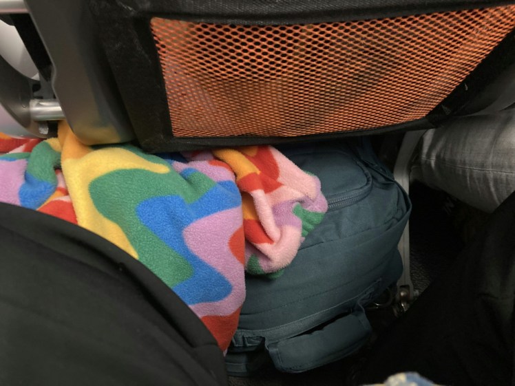 The bag, wedged under the seat of an easyJet plane, with my rainbow fleece wedged alongside it.