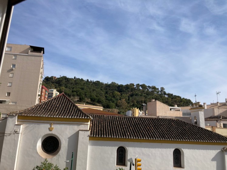 The view of the Gibralfaro, stone walls among the trees on top of a hill, as just about seen from our apartment window.