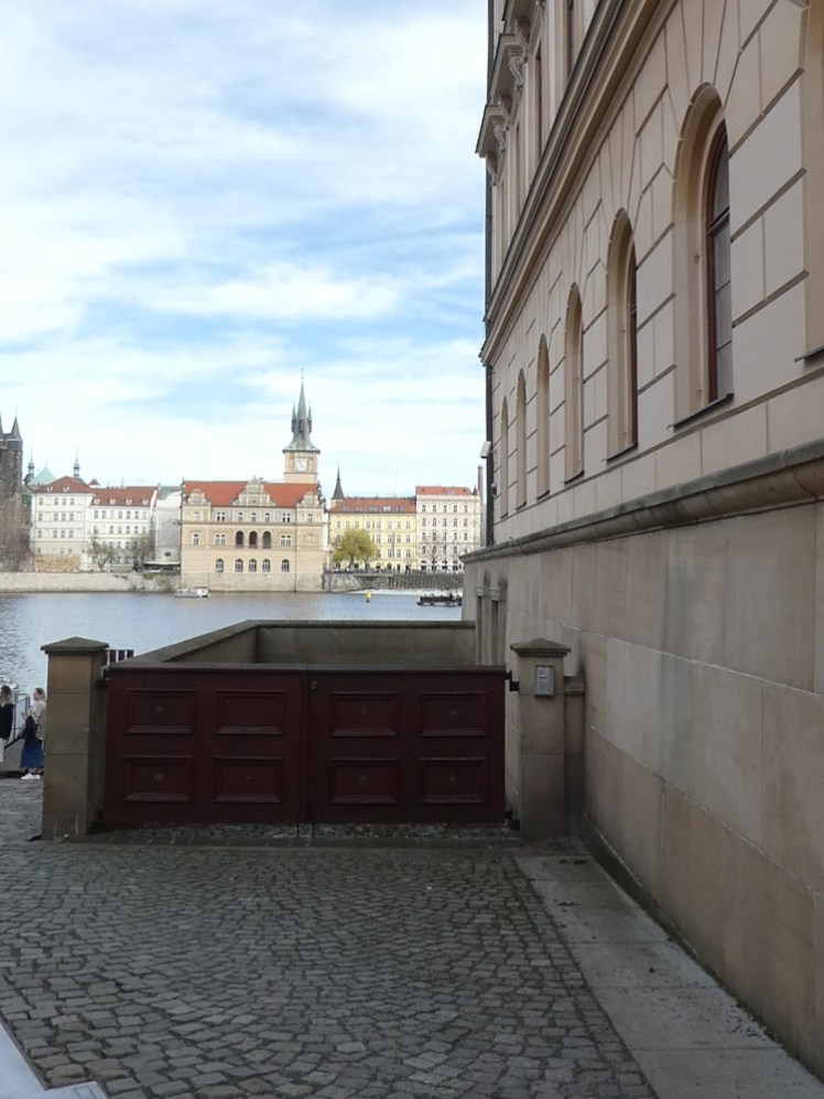 The gate down the side of Liechtenstein Palace, a waist-high wooden gate closing off a square area enclosed by a low wall on the side of the building.