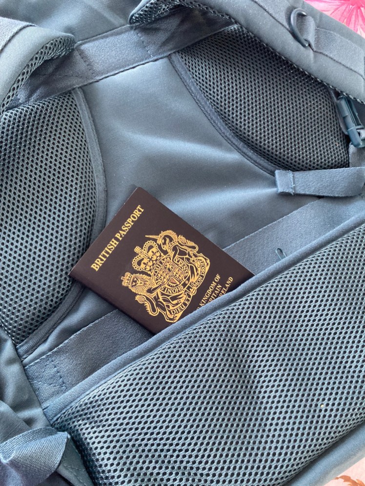A hidden zipped pocket behind the lower back pad with my passport sticking out. Immediately above it is a strap so you can slip it over the handle of your wheely luggage.