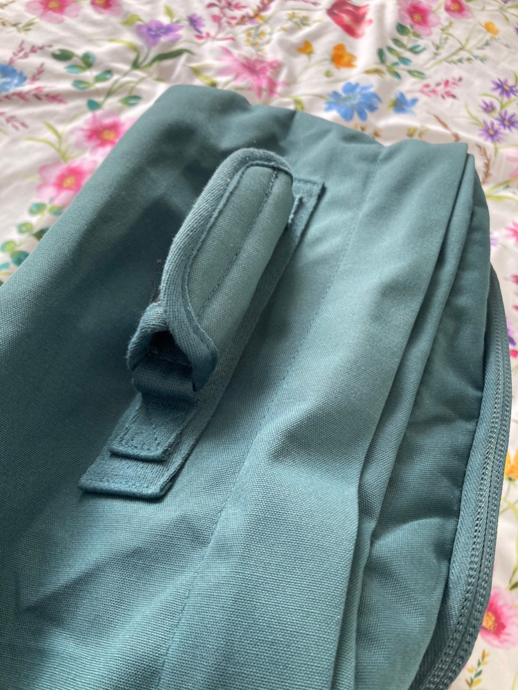 The top grab handle, which is wrapped in a velcro cover of the design usually meant to hold two side handles together.