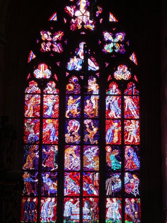 A window in shades of red and blue, with a different person, probably saints or Bible figures, in every panel. These are mosaic-style so there's a lot of detail, especially in the folds of their clothes.