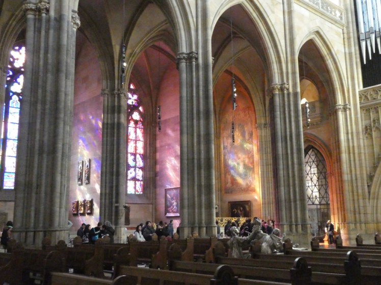 The south aisle with each bay turned into a shallow chapel. The coloured windows in each is casting a pastel glow in purple, pink and orange onto the stone walls.