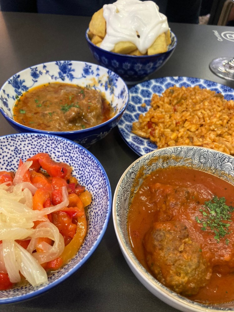 Five tapas at El Clan, all served in blue and white bowls. Everything is somewhere on the red-orange-yellow end of the spectrum so it looks especially pretty in the bowls.