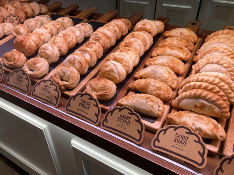 A display of empanadas, some crimped like Cornish pasties and some rolled like giant tortellini, each stamped with its filling.