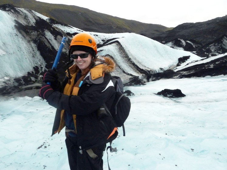 All dressed up for climbing on a glacier striped with volcanic ash, brandishing a climbing axe.
