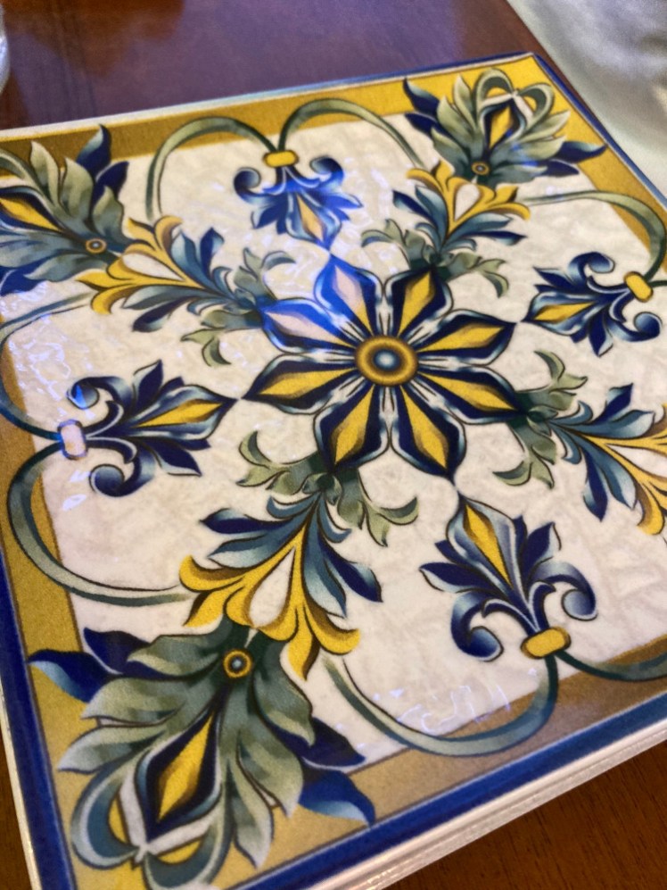 A square plate that looks a bit like a tile with a symmetrical blue, green and yellow pattern on it.