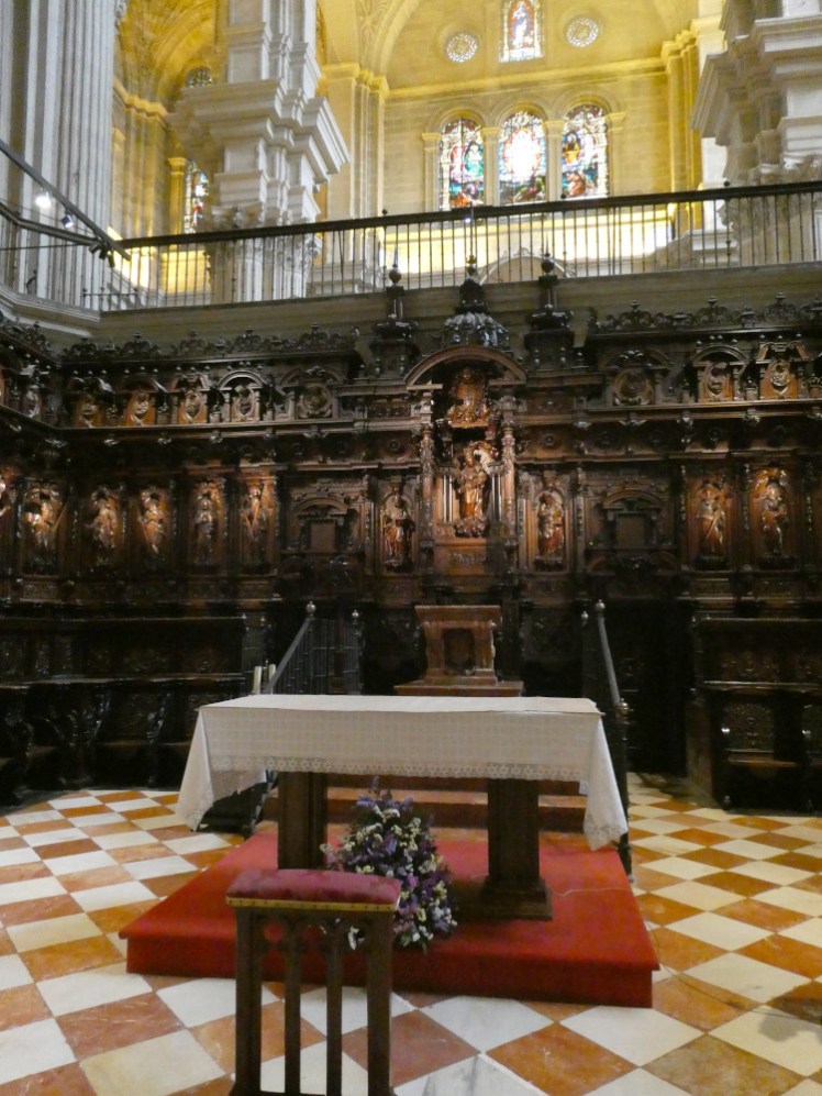 The quire, a wooden "box" with decorative seating and misericords in dark wood and a simple altar with a cloth over it.