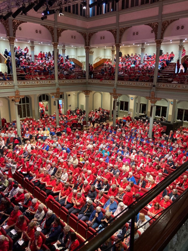 An entire room and balcony full of, mostly, older ladies dressed in red. This is the Trefoil Guild assembled.