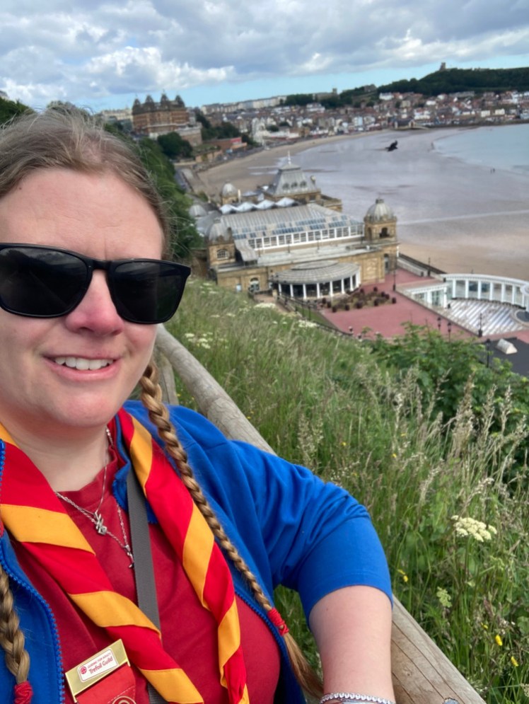 A selfie in my Trefoil "uniform" and neckerchief on top of the cliff overlooking the Spa building on the seashore below.