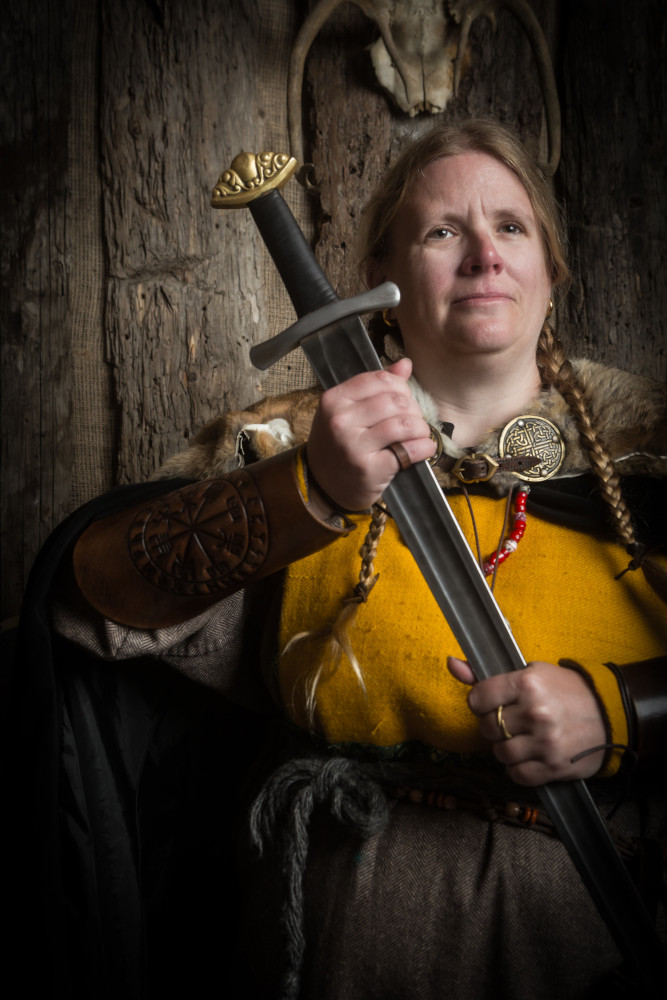 Me with no glasses on, draped in Viking costume and holding a big sword with two hands by the blade.