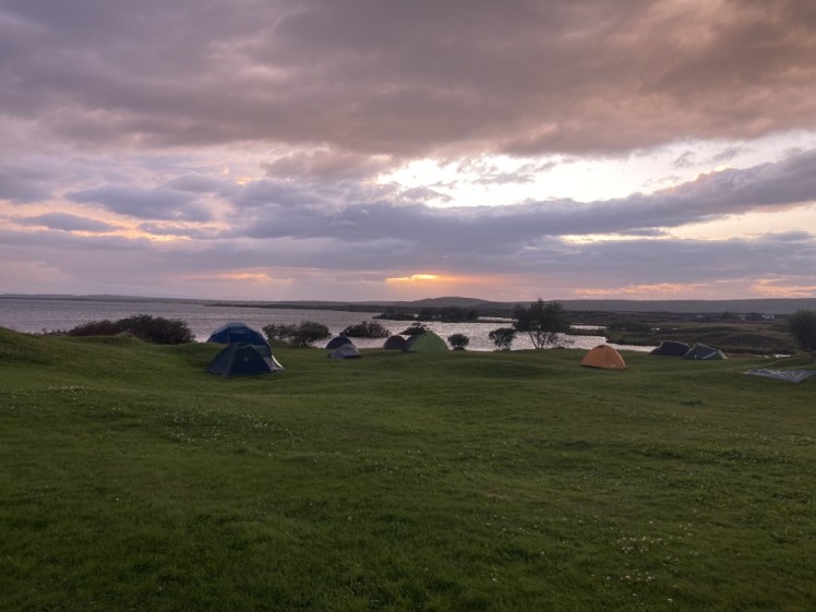 Bjarg campsite's tent field with the lake behind it and a purple-pink sky overhead.