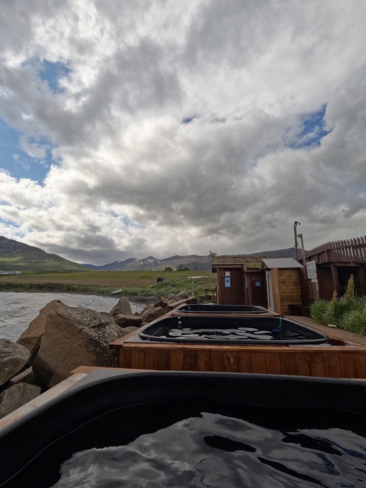 The hot tubs at Haugages, three of them in a row across the beach, set in wooden surrounds, with the fjord off to the left and mountains all around.