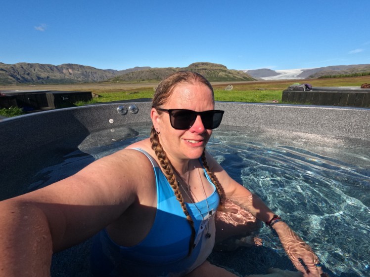 A selfie in a grey plastic hot tub with the glacier in the background.