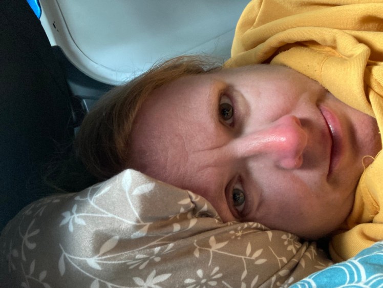Me in my yellow hoodie lying down in the van among patterned pillows.