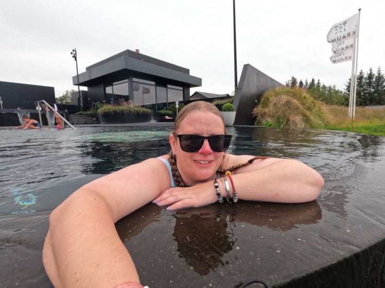 A selfie at Krauma, leaning over the front wall while the rain pitter-patters into the warm water.