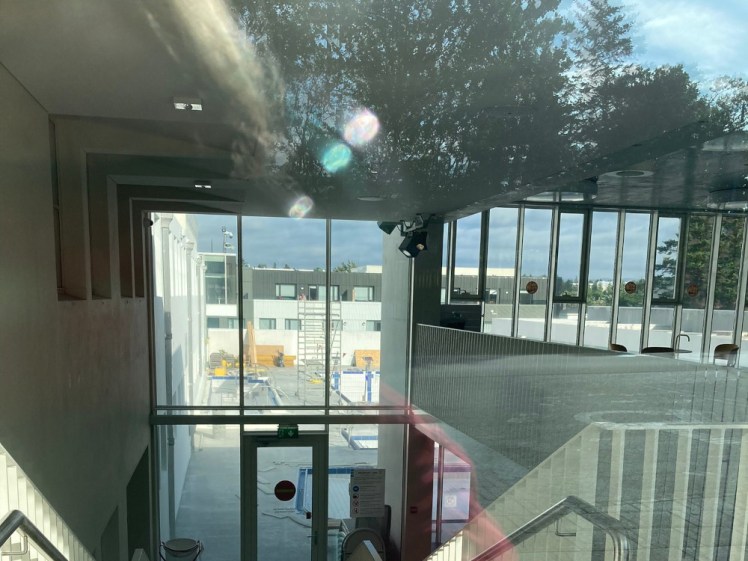 A picture from the glass door of Sundhollin, looking through the building to the pools, which are empty of water and full of machinery.