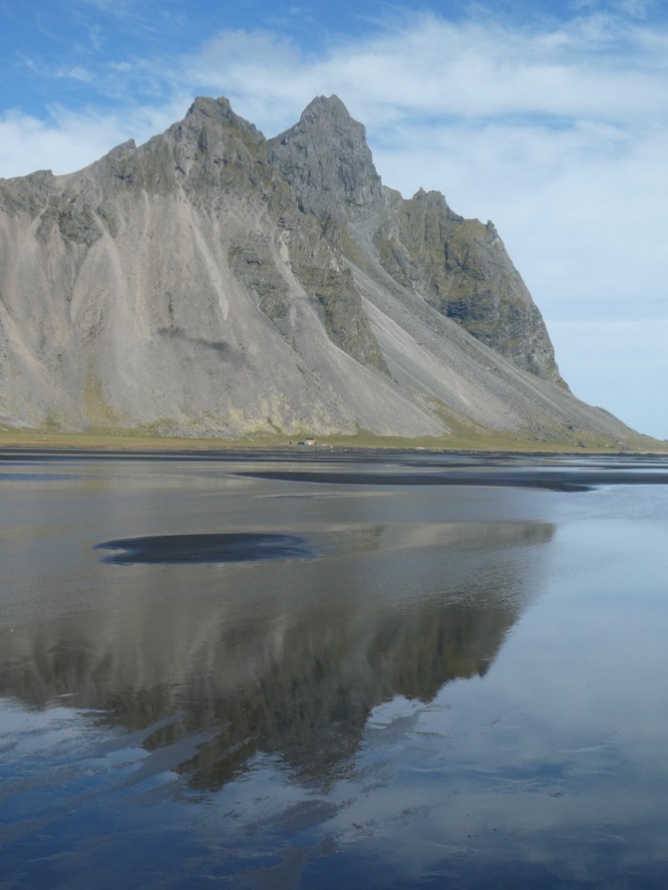 Vestrahorn, a jagged mountain, reflected pretty perfectly in the vast wet black beach at its foot.