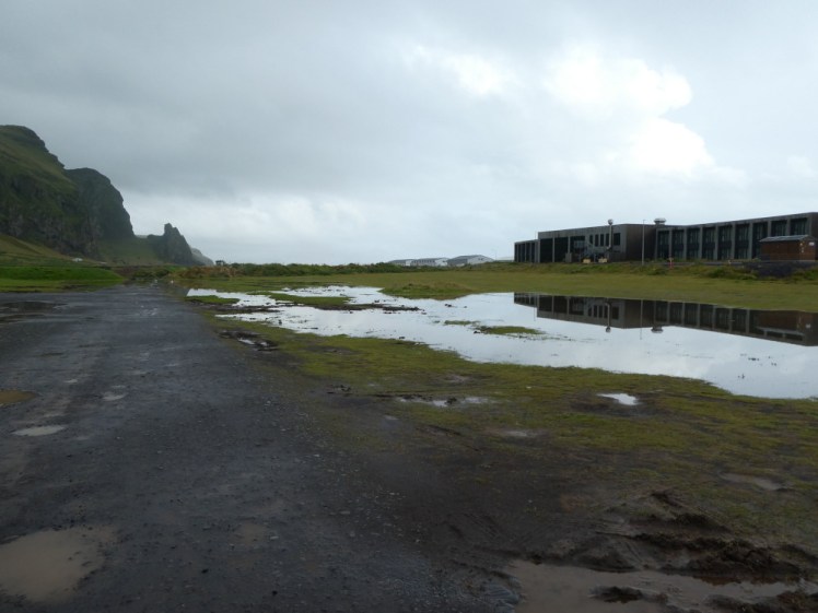 The campsite at Vik under a grey sky. Half the campsite is flooded - not deep but too deep to pitch a tent in and probably too deep and definitely too muddy to park a van on.
