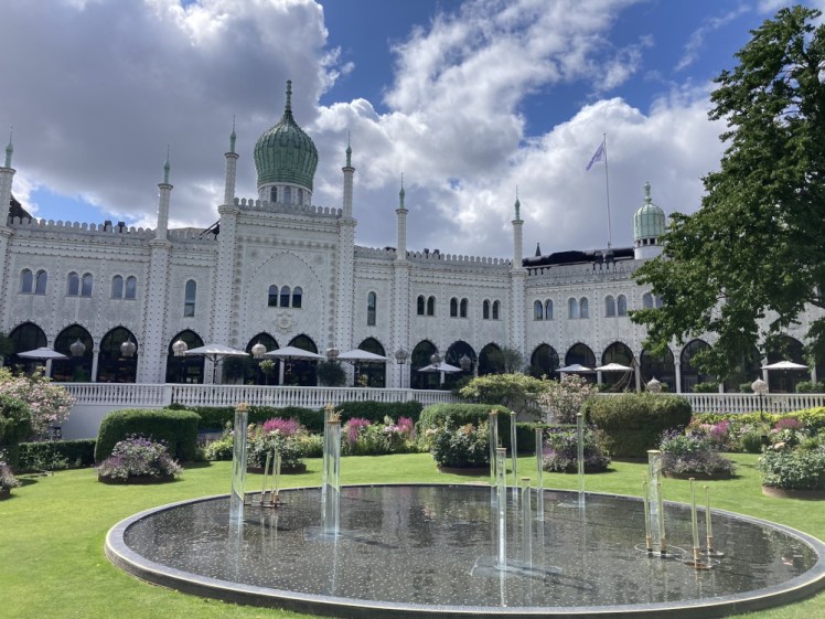The Nimb Hotel, a big white Aladdin-style building with a water feature in front of it. It's daylight so you can't see the several thousand colourful light bulbs that will illuminate it in the evening.